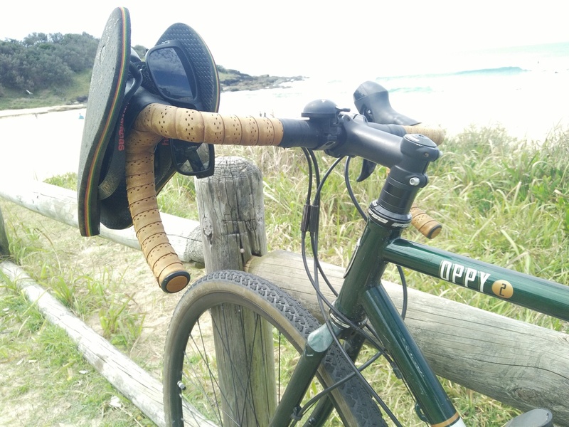 Green bicycle by the sea with a thong (AKA flip-flop) hanging on the handlebars