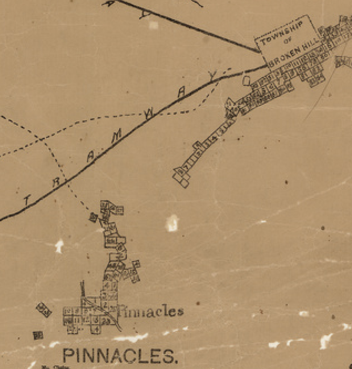 A sepia tinted paper map with black ink lines and lettering indicating a tramway travelling from the township of Broken Hill in the top right to empty space in the mid left. Below left are a collection of squares clustered around the Pinnacles