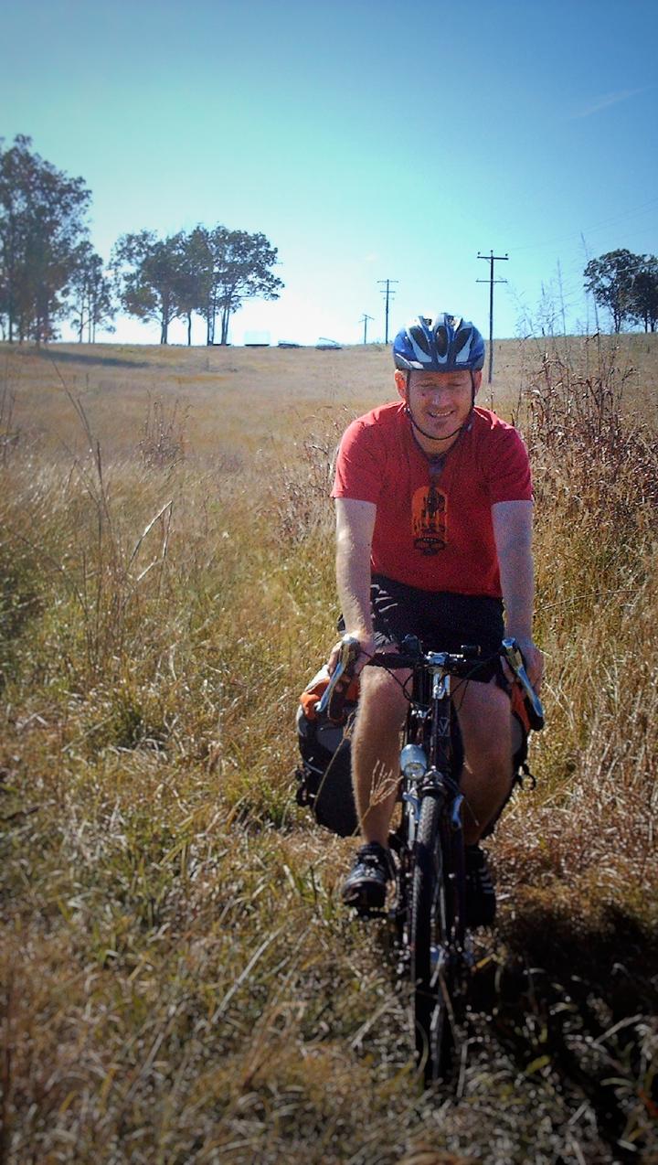Matt cycling along a shortcut through a field