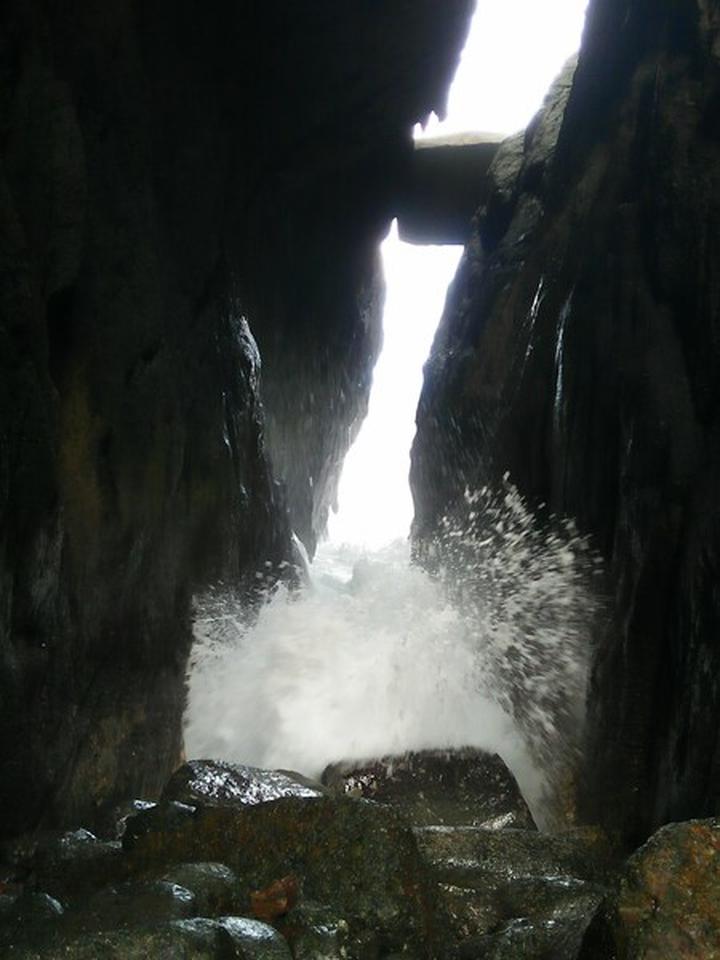 The Hat Head Crevice, black rocks and spray from a breaking wave