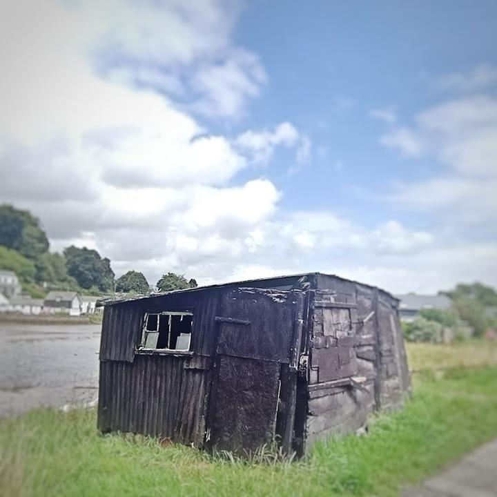 A small black shed, leaning precariously to one side