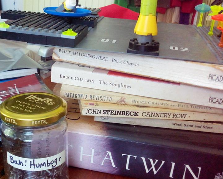 A pile of books with lego and a jar of humbugs