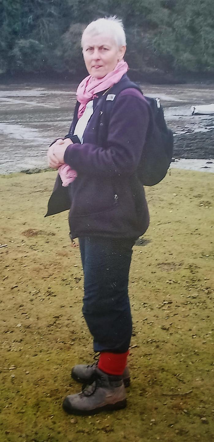 A blurry old photo of my Mum in hiking boots and red socks standing by an estuary